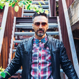 man wearing checkered shirt, leather jacket and jeans bow tie