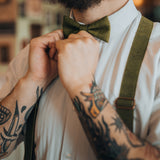 guy with tattoos wearing a green bow tie and suspenders
