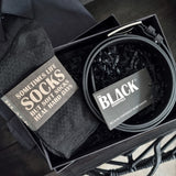 Black socks and belt set with 'The Black Essentials' branding in a box.