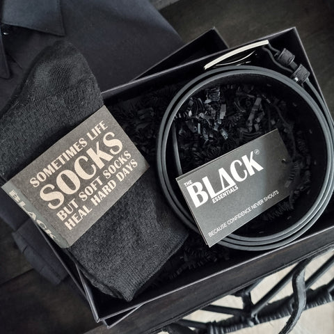 Black socks and belt set with 'The Black Essentials' branding in a box.