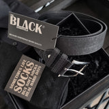 Black belt with a tag and socks in a box, featuring 'The Black Essentials' brand.
