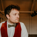 man wearing vest and olive green bow tie