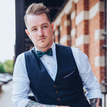 man wearing white shirt and vest with dark green cork bow tie