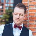 man with vest and dark red bow tie